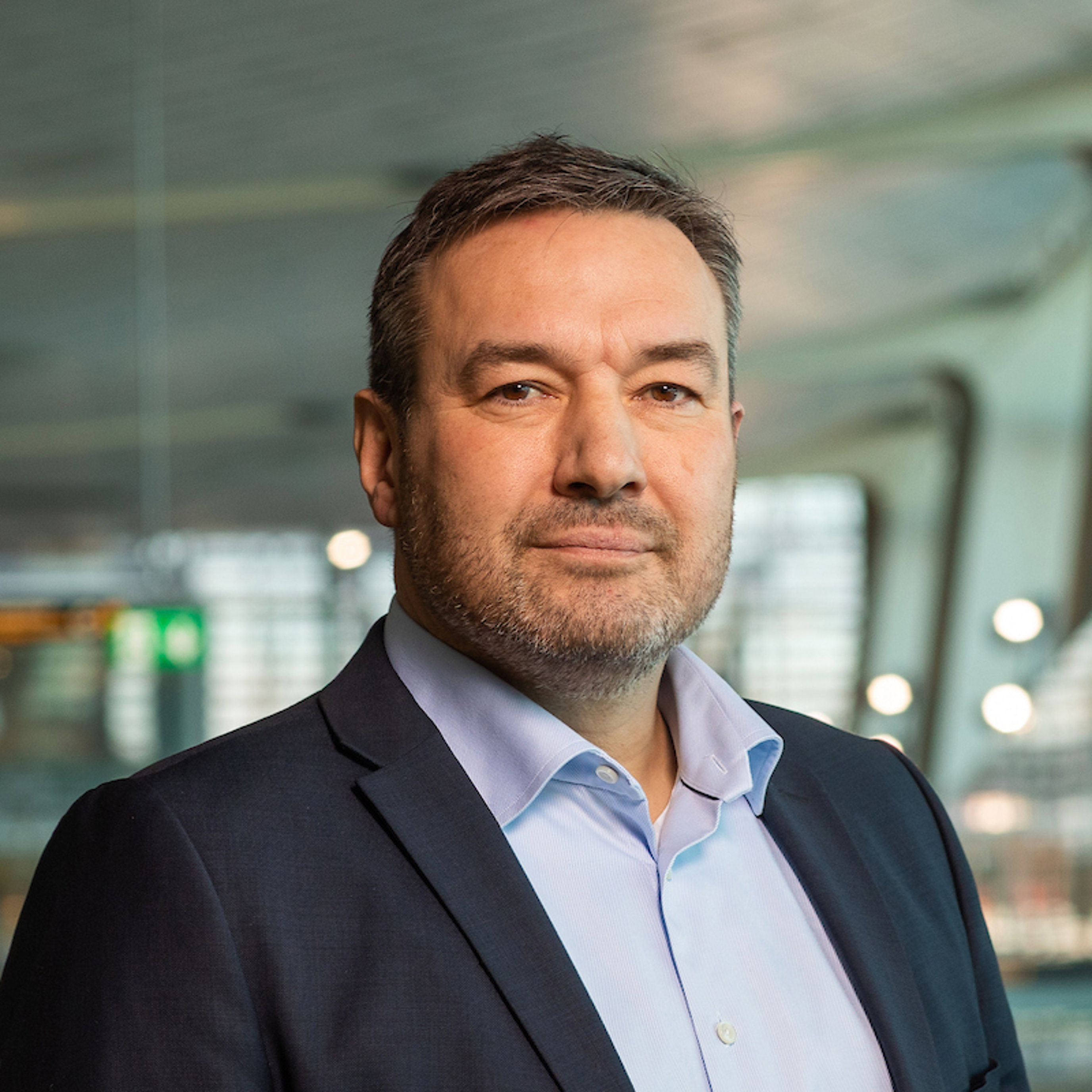 Mann i dress i moderne kontorlokale, ser direkte mot kamera.