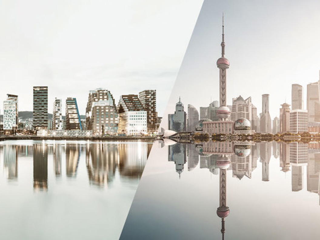 Panoramabilde av moderne bysilhuetter, delt mellom Oslos Barcode-prosjekt og Shanghais skyline, reflektert i vannet.