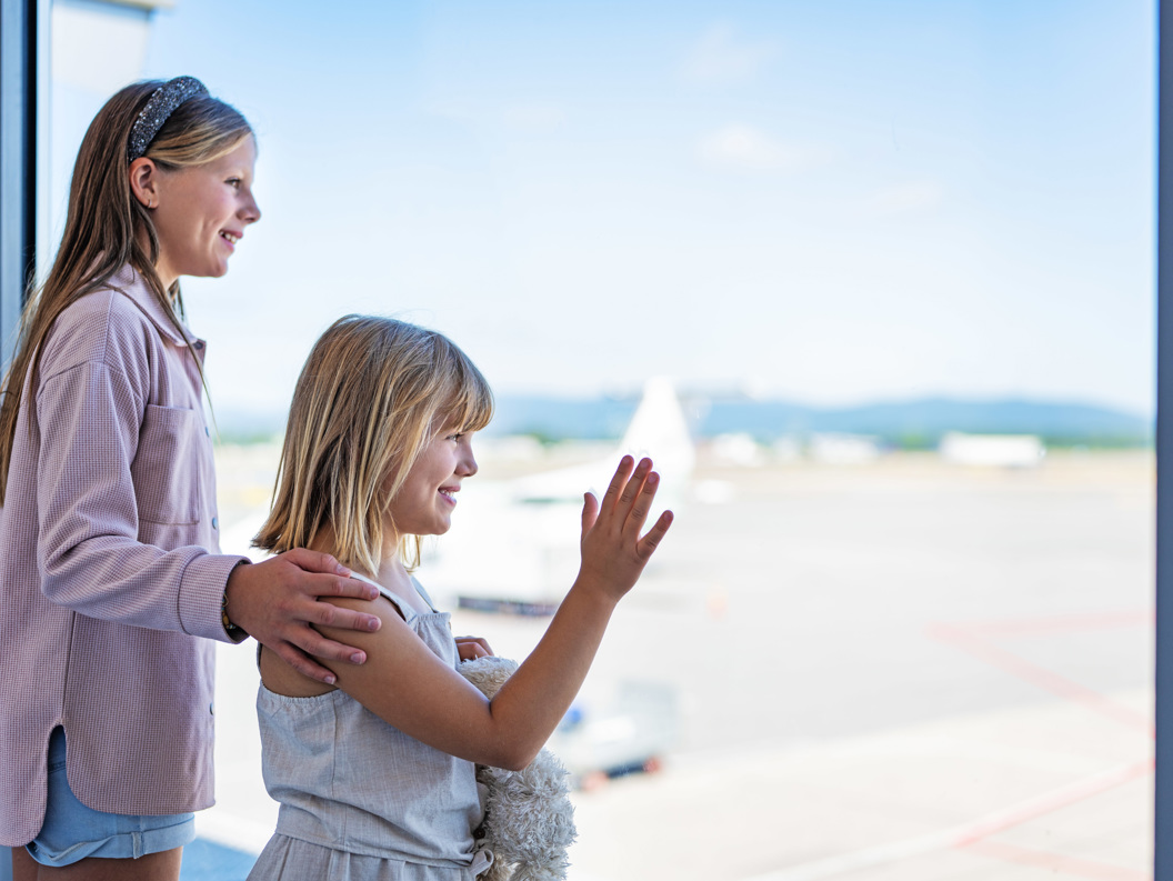 Children looking out a window at the airport